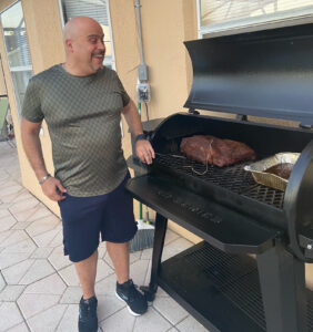 Mike Calvo smiling at the cooked meat on his outdoor grill