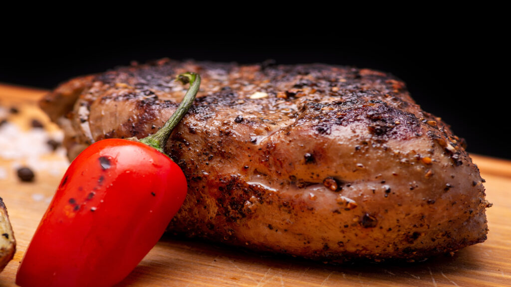Picture of a cooked steak with a red pepper.